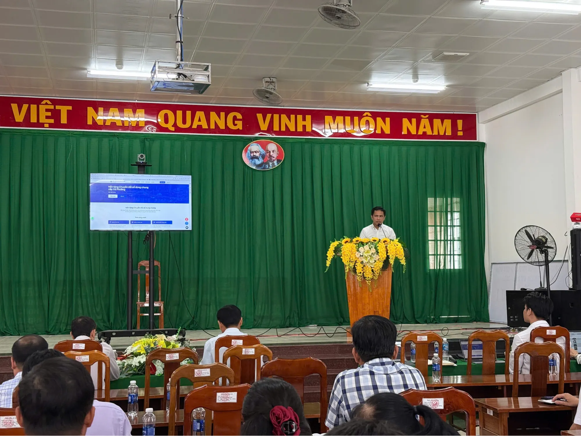 Đại diện HCTECH giới thiệu chi tiết về các tính năng của nền tảng Chuyển đổi số trên màn hình hiển thị tại hội trường Phường Cái Vồn.